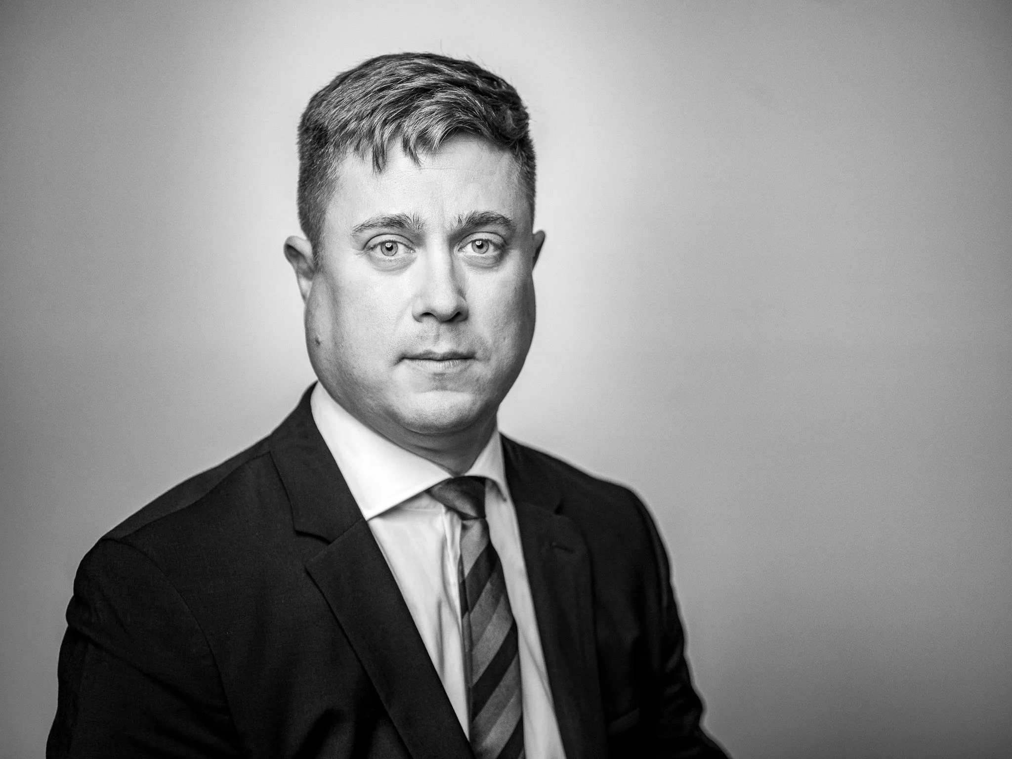 Black and white portrait of a man in a dark suit and striped tie with a composed expression
