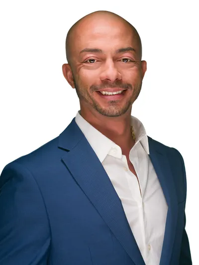 Man in a blue suit and white shirt smiling confidently against a clean white background