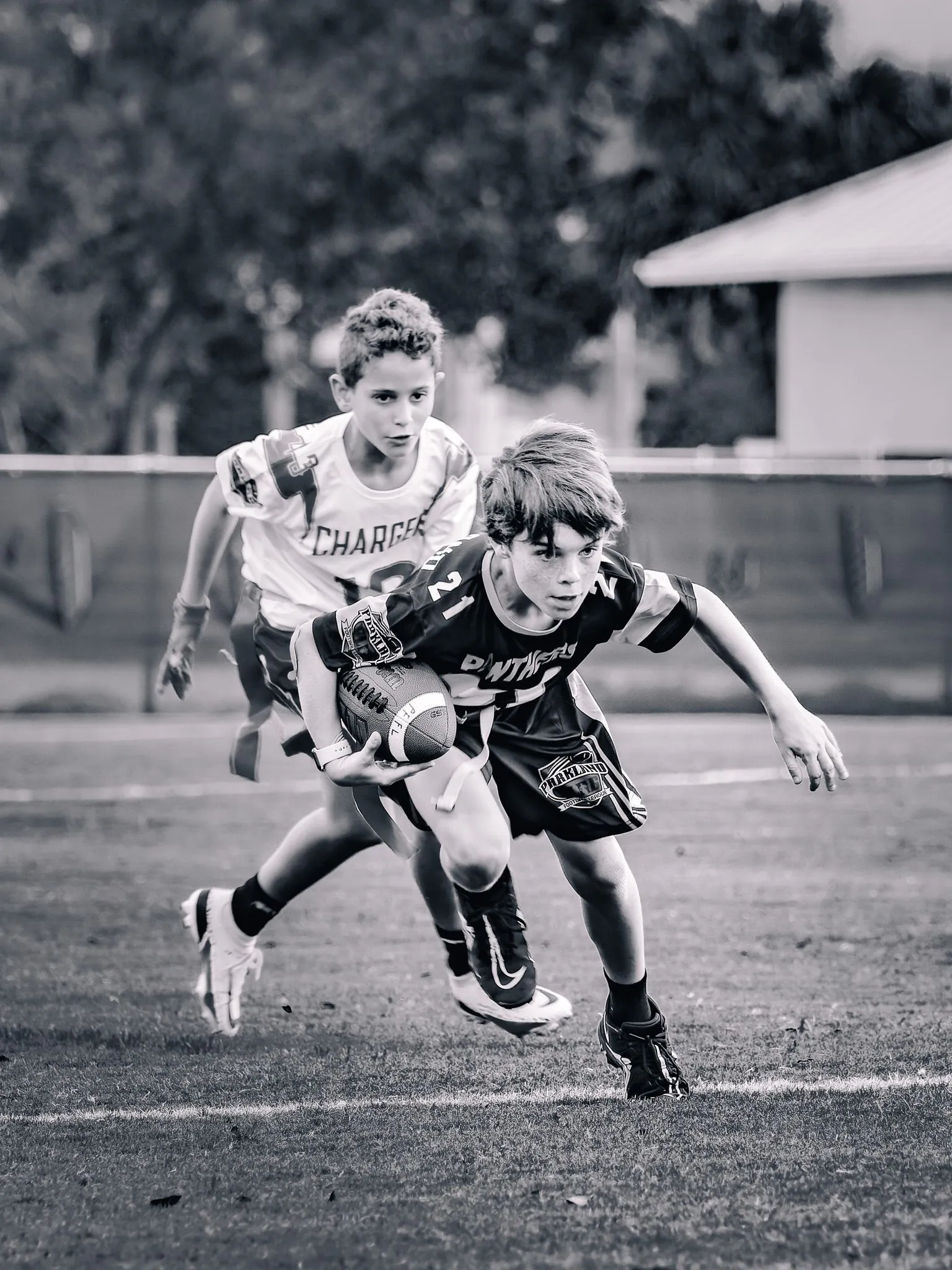 Black and white action shot of a youth football player cutting with the ball past a defender