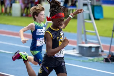 Two young boys sprint to the finish at a youth track and field meet on a blue track