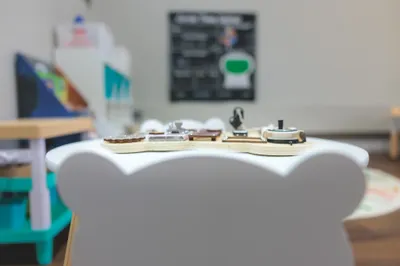 Shallow depth-of-field detail shot of small wooden toys on a bear-shaped chair in a children's learning space