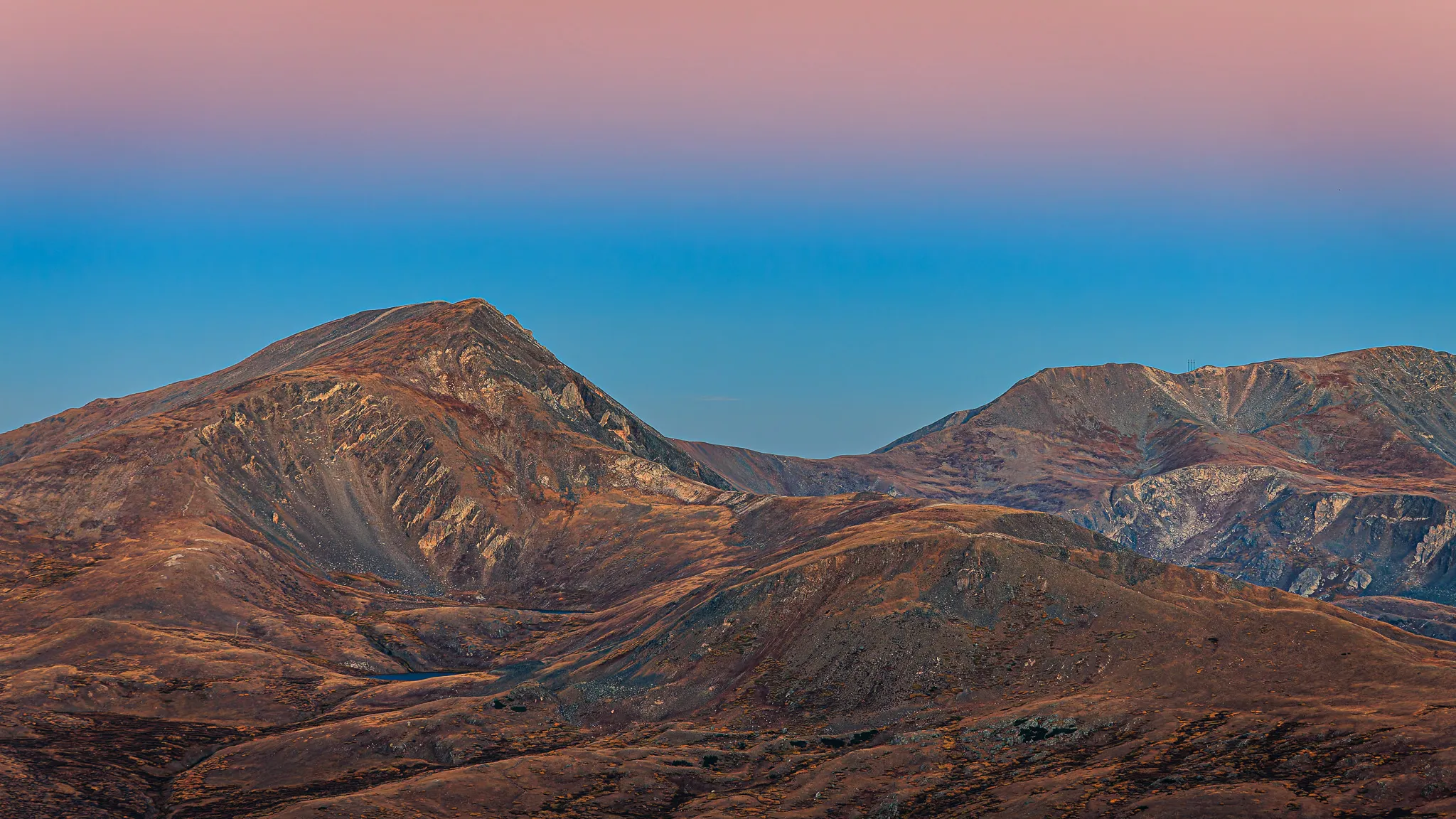 Colorado mountain peaks at twilight with pink and blue gradient sky above barren alpine ridgelines