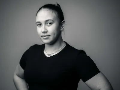 Young woman with hair pulled back in black tee and delicate necklace, calm studio black and white portrait